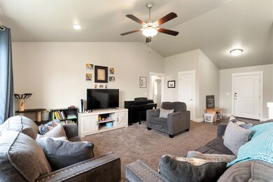Living room with lofted ceiling, carpet, and a ceiling fan