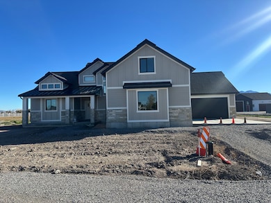 View of front of property featuring stone siding, covered porch, driveway, a metal roof, and an attached garage
