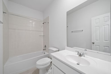 The secondary bath features tile flooring, white c