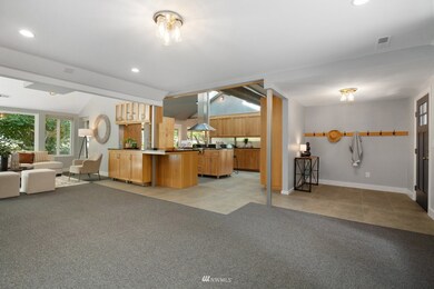 One idea would be to add a half-wall or low bookshelf from the post to the door where the carpet ends, creating a great little library nook in front of the large picture window just out of frame to the right.