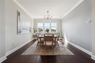 Dining area featuring a chandelier, dark wood finished floors, and ornamental molding