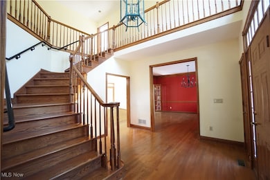 Entrance foyer with a chandelier, wood finished floors, and a towering ceiling
