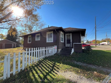 Bungalow-style house featuring a garage, an outdoor structure, and roof with shingles
