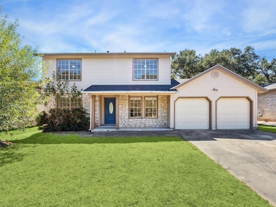 Traditional-style home featuring driveway, a front lawn, stone siding, and an attached garage
