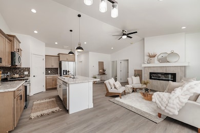 Kitchen with stainless steel appliances, pendant lighting, open floor plan, a high end fireplace, and tasteful backsplash