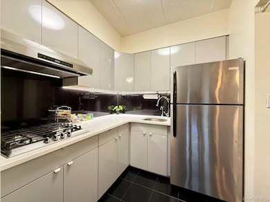 Kitchen featuring stainless steel appliances, backsplash, dark tile patterned floors, a textured ceiling, and modern cabinets