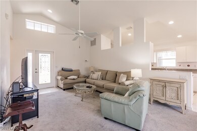 Carpeted living room with high vaulted ceiling, si