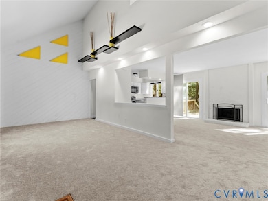 Unfurnished living room featuring light colored carpet, a fireplace with raised hearth, and recessed lighting