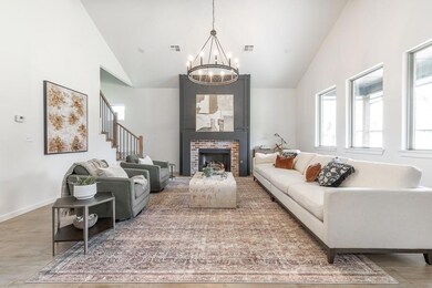 Living area featuring a chandelier, high vaulted ceiling, stairs, and a brick fireplace