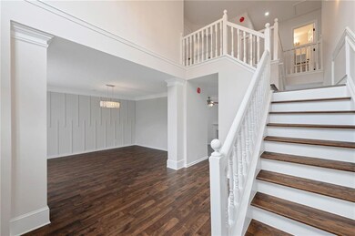 Stairway with wood finished floors, ornate columns, ornamental molding, and a towering ceiling