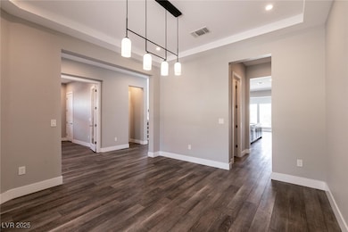 Unfurnished room featuring a tray ceiling, dark wo