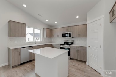 Kitchen featuring light brown cabinets, appliances with stainless steel finishes, modern cabinets, lofted ceiling, and recessed lighting