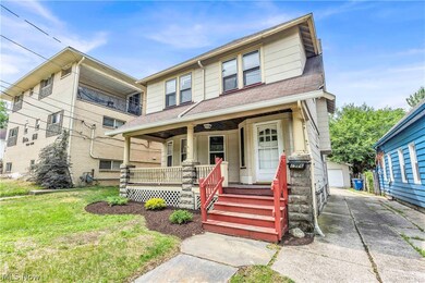 View of front of home with a porch, a garage, an outbuilding, and a front yard