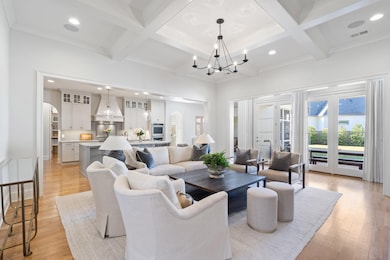 Living area featuring arched walkways, recessed lighting, light wood-style floors, beam ceiling, and coffered ceiling