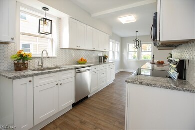 Kitchen close up with vinyl flooring, granite countertops, new appliances with stainless steel finishes, tile backsplash, and new fixtures and white quaker style cabinets