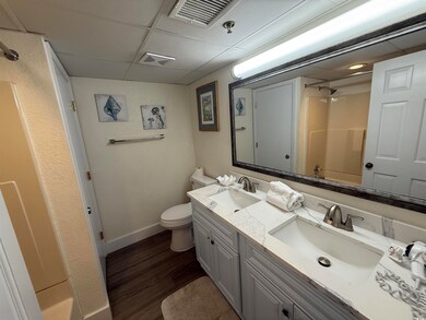 Bathroom with a paneled ceiling, a shower, double vanity, and wood finished floors