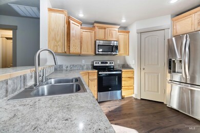 Kitchen with stainless steel appliances, light countertops, light brown cabinetry, dark wood finished floors, and recessed lighting