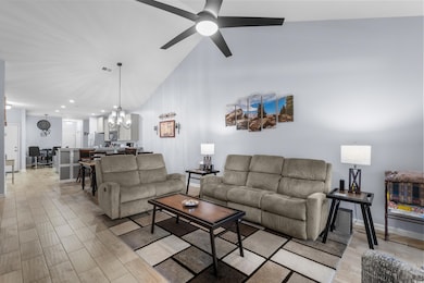 Living room featuring a chandelier, a ceiling fan, high vaulted ceiling, light wood-type flooring, and recessed lighting