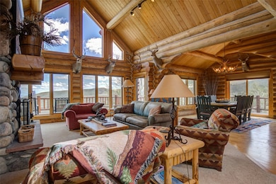 Living room with a notable chandelier, wooden ceiling, high vaulted ceiling, beam ceiling, and track lighting