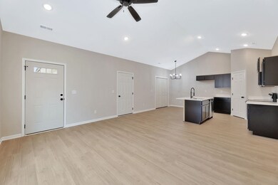 Kitchen featuring a kitchen island with sink, open floor plan, a chandelier, light wood-style flooring, and pendant lighting