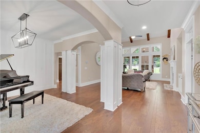 Entrance foyer with decorative columns, arched walkways, wood finished floors, a ceiling fan, and recessed lighting