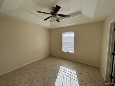 Unfurnished room featuring a raised ceiling, baseboards, a ceiling fan, and light tile patterned flooring
