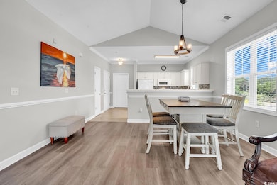 Dining space featuring light wood finished floors, a chandelier, and vaulted ceiling