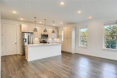 Kitchen featuring hanging light fixtures, a center island with sink, tasteful backsplash, stainless steel appliances, and dark wood-style floors