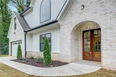 Entrance to property with brick siding, board and batten siding, driveway, french doors, and roof with shingles