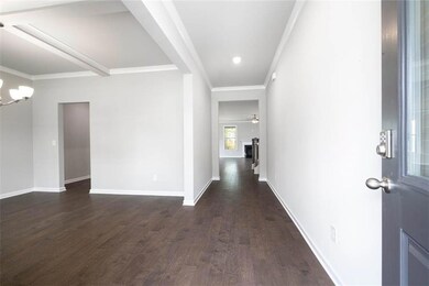 Entryway featuring dark wood-style flooring, a chandelier, baseboards, crown molding, and ceiling fan
