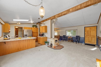 Kitchen with a wood stove, vaulted ceiling, light countertops, open floor plan, and stainless steel fridge with ice dispenser