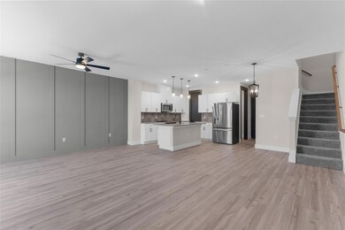 Unfurnished living room with sink, light hardwood / wood-style flooring, and ceiling fan with notable chandelier
