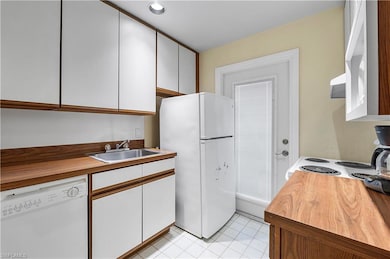 Kitchen with light tile patterned floors, white ca