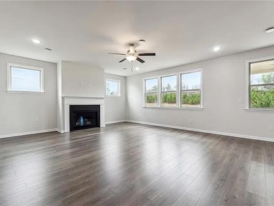Unfurnished living room featuring ceiling fan, a fireplace, dark wood-style flooring, and recessed lighting