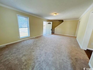 Unfurnished living room featuring ornamental molding, baseboards, and carpet