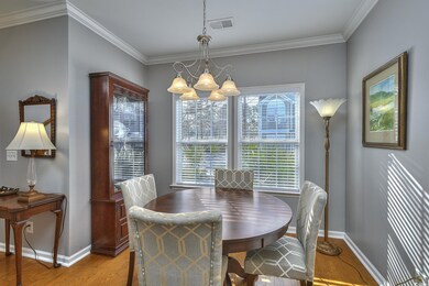 Dining space with visible vents, baseboards, light wood-style flooring, an inviting chandelier, and crown molding