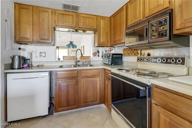 Kitchen with sink, white appliances, and light tile patterned floors