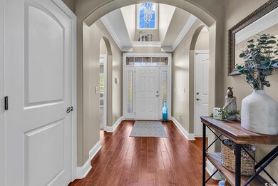 Foyer featuring arched walkways, ornamental molding, dark wood-type flooring, and baseboards