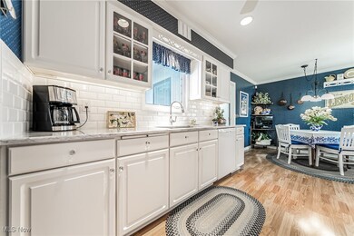 Kitchen featuring tasteful backsplash, white dishwasher, sink, light wood-type flooring, and white cabinetry