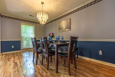 Dining area with ornamental molding, wood finished floors, a chandelier, and a textured ceiling