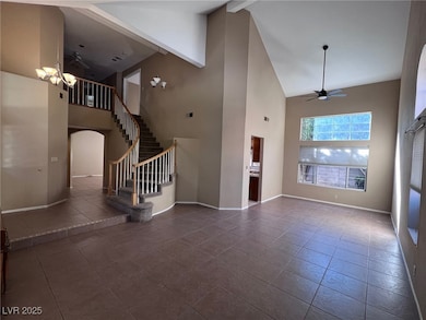 Unfurnished living room featuring a ceiling fan, high vaulted ceiling, arched walkways, stairway, and beamed ceiling