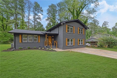 Split level home with brick siding, a front lawn, and driveway