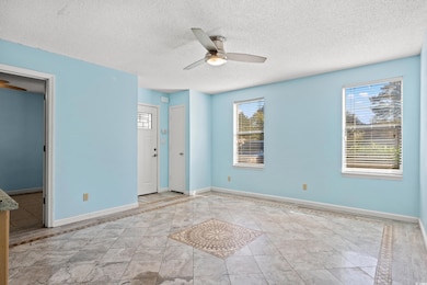 Unfurnished bedroom featuring a textured ceiling, inlaid floor details, a ceiling fan, and light tile patterned flooring