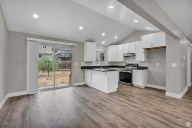 Kitchen with dark countertops, backsplash, electric stove, white cabinetry, and lofted ceiling