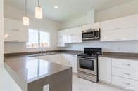 Kitchen with stainless steel appliances, white cabinets, and hanging light fixtures