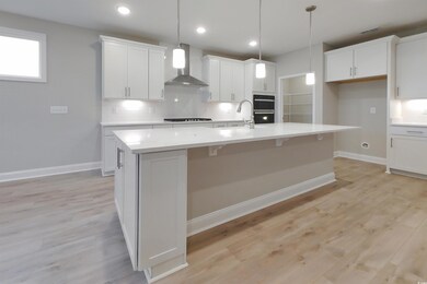 Kitchen featuring wall chimney range hood, an isla