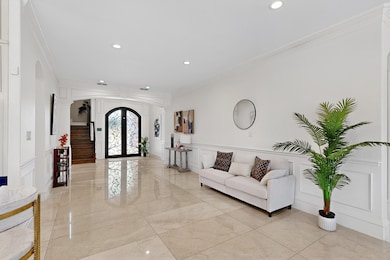 Living room with a decorative wall, arched walkways, ornamental molding, recessed lighting, and french doors