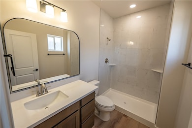 Full bath with toilet, tiled shower, wood finished