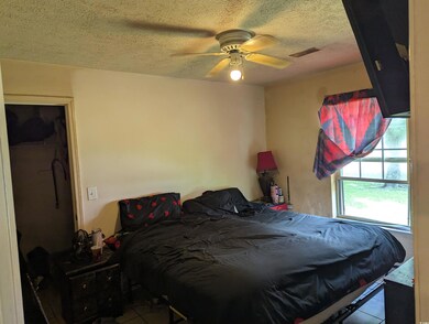 Bedroom with tile patterned floors, a textured ceiling, and ceiling fan