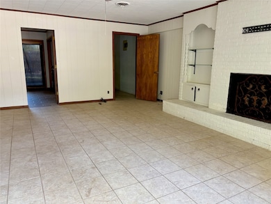 Unfurnished living room featuring wooden walls, crown molding, a fireplace, and light tile patterned floors